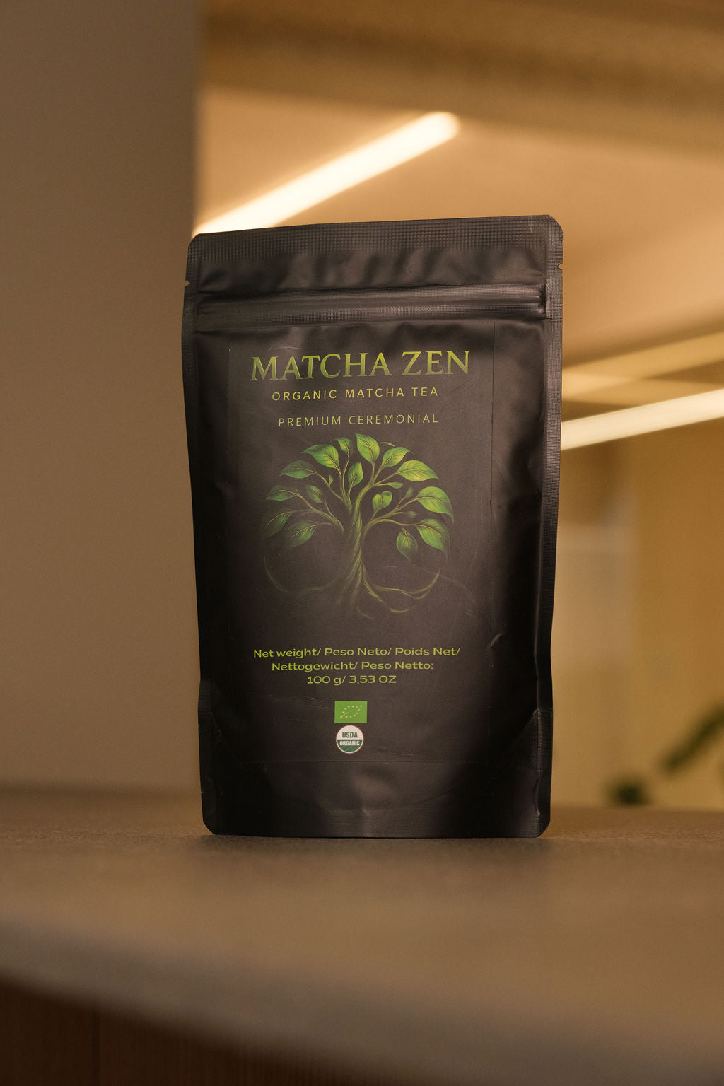 Bolsa de Matcha Zen ceremonial ecológico de pie sobre una superficie clara con el fondo desenfocado