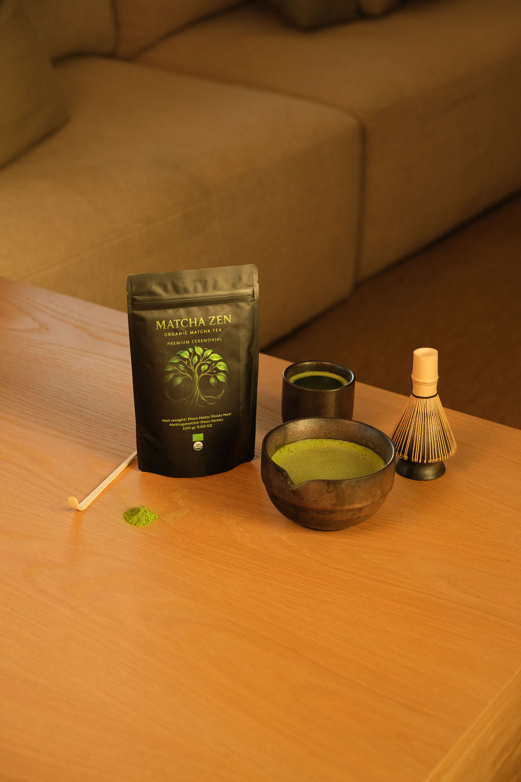 Cuenco con matcha batido, chasen de bambú, taza y bolsa de Matcha Zen sobre una mesa de madera
