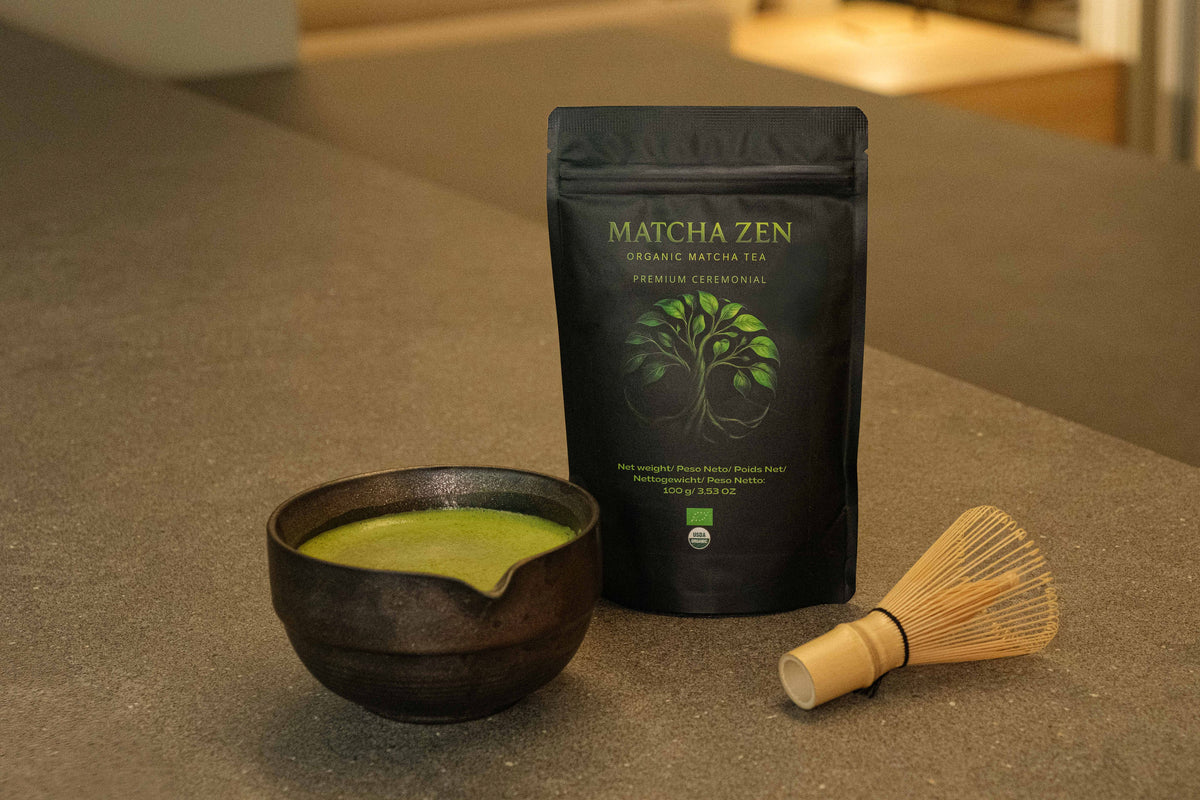 Cuenco con matcha recién batido y un chasen de bambú al lado sobre una encimera de piedra