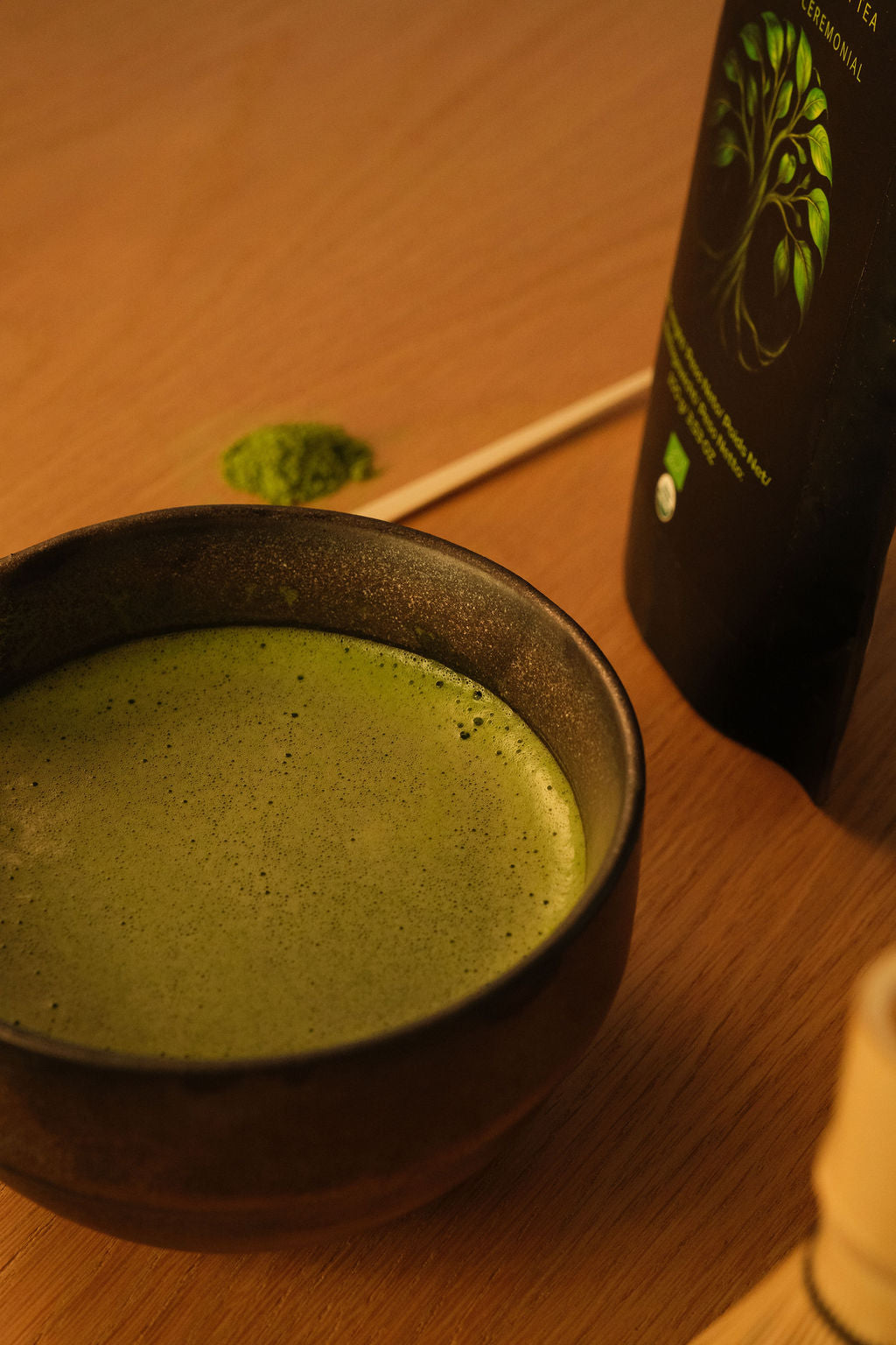 Primer plano de un cuenco oscuro con matcha recién batido, un líquido verde y espumoso