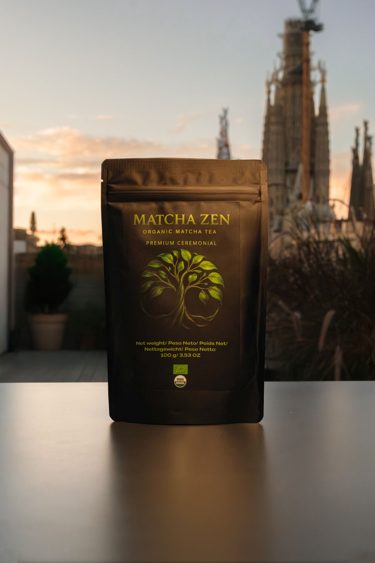Bolsa de Matcha Zen en una terraza con la Sagrada Familia y el cielo del atardecer al fondo