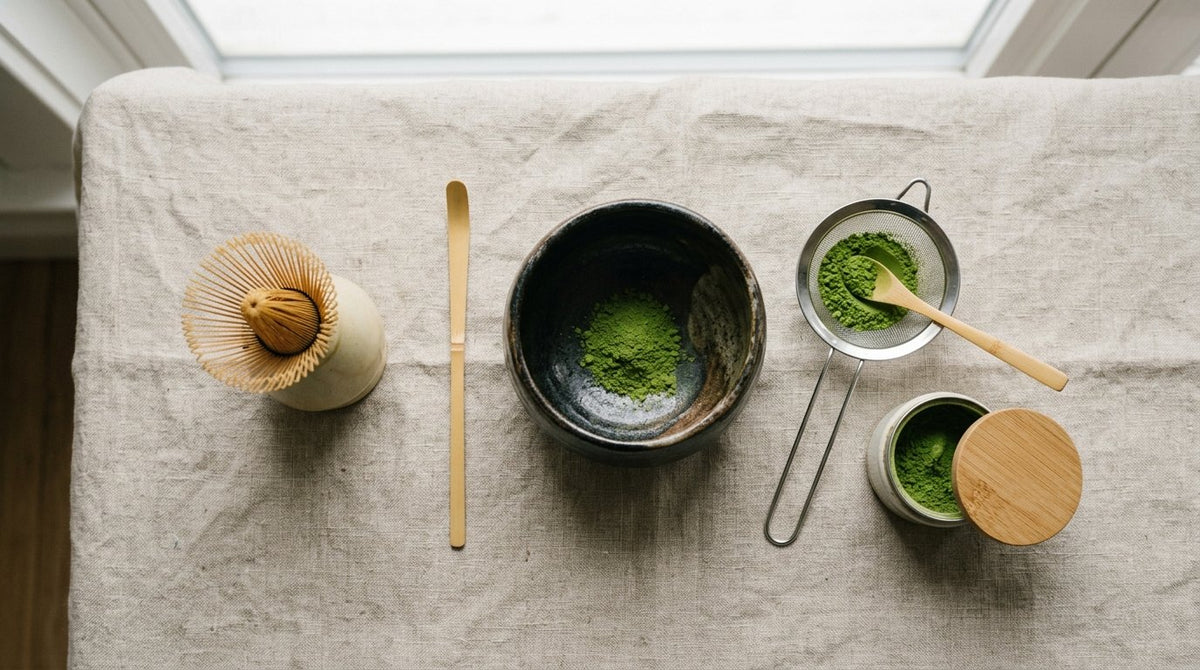 Utensilios de matcha ordenados sobre lino: batidor y cuchara de bambu, cuenco de ceramica y tamiz